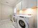 Laundry room with white cabinets, tile floor, and modern washer and dryer at 1560 Tapestry Rdg, Lawrenceville, GA 30045