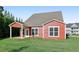 Red two-story house with covered patio, green lawn, and mature trees at 100 Academy Ln, Canton, GA 30114