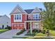 Charming two-story red house with an inviting front porch, attached garage, and landscaped yard at 100 Academy Ln, Canton, GA 30114