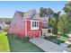 A two-story red home stands with its attached garage, viewed from an angle showcasing the front and side at 100 Academy Ln, Canton, GA 30114