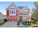 Two-story red home with a covered front porch, attached garage, and landscaped yard at 100 Academy Ln, Canton, GA 30114