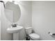 A half bathroom with a pedestal sink, toilet, and circular mirror at 100 Academy Ln, Canton, GA 30114