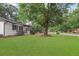 Spacious green lawn with mature trees and a charming house in the background at 1396 Iron Gate Blvd, Jonesboro, GA 30238