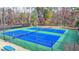 Two blue tennis courts in a community area with green fencing and trees at 317 Devonshire Dr, Alpharetta, GA 30022