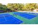 Three blue tennis courts, surrounded by green landscaping at 5530 Highland Preserve Dr, Mableton, GA 30126