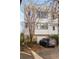 White three-story home with gray SUV in driveway, mature trees and landscaping at 9129 Selborne Ln, Chattahoochee Hills, GA 30268