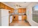 Compact kitchen featuring wood cabinets, white appliances, and door to backyard at 61 Macland Springs Dr, Dallas, GA 30157