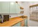 Bright laundry room with light green cabinets, wood countertops, and a window at 4924 Red Cliff Ct, Powder Springs, GA 30127