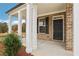 Covered front porch with white columns, black front door, and brick exterior at 5392 Heron Bay Blvd, Locust Grove, GA 30248