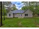 Backyard view of a ranch-style home with a grassy yard and trees at 4230 Moore Rd, Conley, GA 30288