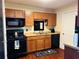Compact kitchen with wood cabinets, black appliances, and a decorative floor mat at 2711 Greystone Ct, Austell, GA 30106