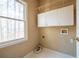 Laundry room with white cabinets, window, and space for washer and dryer at 514 Lovinggood Ct, Woodstock, GA 30189