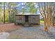 Rear view of the log cabin with a gravel driveway and steps leading to the entrance at 7865 Nesbit Ferry Rd, Sandy Springs, GA 30350
