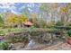Picturesque backyard with a pond, lush greenery, and a charming red cabin at 7865 Nesbit Ferry Rd, Sandy Springs, GA 30350