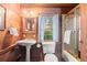 Bathroom with pedestal sink, shower, toilet, wood paneling and window at 7865 Nesbit Ferry Rd, Sandy Springs, GA 30350