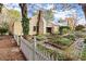Exterior view of a charming farmhouse with a stone chimney, white picket fence, and gardens at 7865 Nesbit Ferry Rd, Sandy Springs, GA 30350