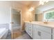 Modern bathroom with double vanity, soaking tub, and doorway to bedroom at 7640 Homer Dr, Cumming, GA 30028
