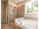 Bathroom featuring tile shower, soaking tub, and large window at 7640 Homer Dr, Cumming, GA 30028