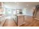 Open concept kitchen and living room with island, hardwood floors, and staircase at 7640 Homer Dr, Cumming, GA 30028