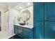Modern bathroom with teal cabinets, marble countertop and a large round mirror at 1900 Harper Nw Rd, Atlanta, GA 30318
