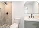 Modern bathroom featuring a walk-in shower, gray vanity, and arched mirror at 6709 Londonderry Dr, Morrow, GA 30260