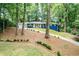 Blue two-story home nestled among lush trees with a paved driveway at 495 Valley Ne Ln, Atlanta, GA 30328