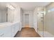 Main bathroom with double vanity, glass shower, and wood-look flooring at 6949 Melody Dr, Buford, GA 30518