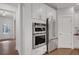 Kitchen featuring stainless steel double oven and refrigerator, white cabinets, and hardwood floors at 6101 Marigold Way, Atlanta, GA 30349