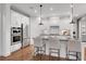 Modern white kitchen with stainless steel appliances, island with seating, and hardwood floors at 6101 Marigold Way, Atlanta, GA 30349