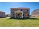 Backyard view of a two-story brick home with a covered patio and grassy lawn at 224 Chiswick Loop, Stockbridge, GA 30281