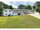 Inviting white brick home with black trim, large lawn, and paved driveway on sunny day at 5573 Prince Phillip Way, Stone Mountain, GA 30087