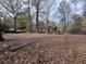 Expansive, wooded backyard with fallen leaves and a glimpse of the house in the distance at 6460 Highway 20 S, Covington, GA 30016