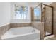 Modern bathroom with soaking tub, tiled walls, shower, and window view at 1495 Auburn Glen Rd, Dacula, GA 30019