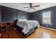Bedroom with dark accent wall, wood floors, ceiling fan, and ample natural light at 6214 Hagin St, Douglasville, GA 30134