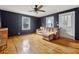 Living room with dark painted walls, hardwood floors, a ceiling fan, and a tan sectional sofa at 6214 Hagin St, Douglasville, GA 30134