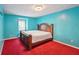 Bedroom with teal walls, red carpet, wooden bed, and window at 1769 Cord Ct, Tucker, GA 30084