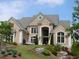 Beautiful brick home with arched entryway, lush landscaping, and a gray roof at 3229 Carmichael Pl, Duluth, GA 30097