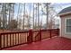 Red wooden deck overlooking fenced backyard with trees and neighboring homes at 1547 Welch Ct, Suwanee, GA 30024
