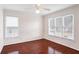 Spacious bedroom featuring hardwood floors, white walls, and multiple windows with blinds at 1547 Welch Ct, Suwanee, GA 30024