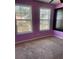 Bright bedroom with two large windows, purple walls, and neutral carpeting at 1276 Huntington Place Cir, Lithonia, GA 30058