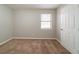 Spacious, vacant bedroom with large window and carpeting at 5136 Huxley Rd, Stone Mountain, GA 30088