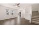 Living room with wood-look floors, white walls, ceiling fan, and carpeted stairs at 979 Cades Walk, Lawrenceville, GA 30045