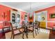 Formal dining room with chandelier, glass table, china cabinet, and coral walls at 2111 Cooper Lake Se Rd, Smyrna, GA 30080
