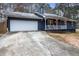 Front view of a charming ranch home with a white garage door and a spacious driveway at 155 Meadowbrook Dr, Mcdonough, GA 30253
