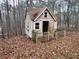 A small shed with pink trim, situated in a wooded area at 1447 Upper Sweetwater Se Trl, White, GA 30184