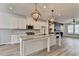 Modern white kitchen with island, pendant lighting, stainless steel appliances, and stone fireplace at 2689 Richmond Row, Suwanee, GA 30024