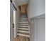 Staircase with white and wood treads, gray wainscoting, and a view towards a doorway at 2689 Richmond Row, Suwanee, GA 30024