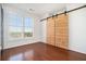Bright bedroom with hardwood floors, sliding barn door, and large window with plantation shutters at 3334 Peachtree Ne Rd # 908, Atlanta, GA 30326