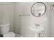 Simple bathroom with pedestal sink, toilet, and round mirror at 576 Rockwell Sw St, Atlanta, GA 30310