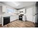 Galley kitchen with white cabinets, black appliances, and wood-look floors at 1102 Forest East Dr, Stone Mountain, GA 30088